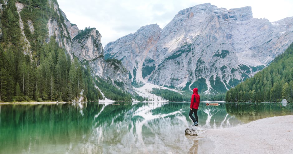Person standing by the scenic Lake Braies with majestic Dolomite mountains reflected in the water