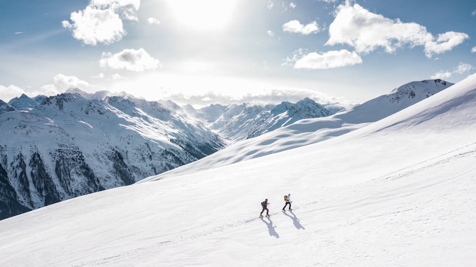 Two skiers climbing a sunlit snowy mountain slope in Ischgl, Austria, during winter